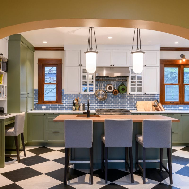 Image shows a kitchen with green cabinets and black-and-white checkered floors.
